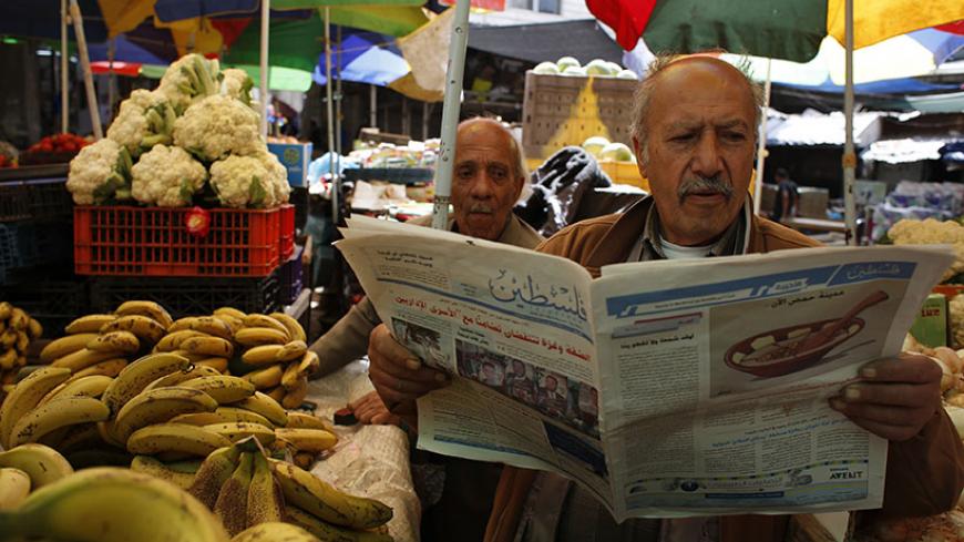 A Palestinian man selling fruits and vegetables reads a copy of a pro-Hamas newspaper, Palestine, at a market in the West Bank city of Ramallah May 10, 2014. The Palestinian authority had allowed the distribution of the pro-Hamas Palestine newspaper in the West Bank on Saturday after the Hamas-run government in the Gaza Strip said on Wednesday it had relaxed a ban on Palestinian newspapers published outside the enclave as a gesture of reconciliation to rival group Fatah after their unity deal last month. RE