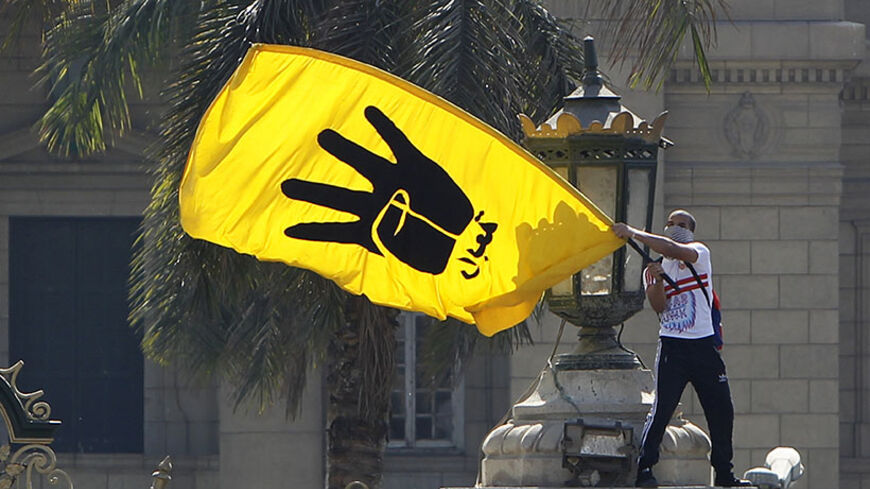 A student supporter of the Muslim Brotherhood and ousted Egyptian President Mohamed Mursi waves the yellow flag bearing the four-fingered Rabaa sign during a demonstration outside Cairo University May 14, 2014. The demonstration was held by members of the Muslim Brotherhood and the pro-Mursi Anti-Coup National Alliance against the military, interior ministry and presidential candidate Abdel Fattah al-Sisi, the former army chief who deposed the Brotherhood's Mursi. The "Rabaa" sign is a reference to the poli