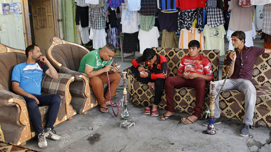 Iraqi Shi'ite youths smoke water pipes at an outdoor cafe in Sadr City in Baghdad April 29, 2014. Iraq is now gripped by its worst violence since the heights of its 2005-2008 sectarian war, and Sunni Islamist insurgents who target Shi'ites have been regaining ground in the country over the past year. But despite the instability, daily life continues in poor Shi'ite neighbourhoods of Baghdad such as Al-Fdhiliya and Sadr City - a sprawling slum marred by poor infrastructure and overcrowding.  REUTERS/Ahmed Ja