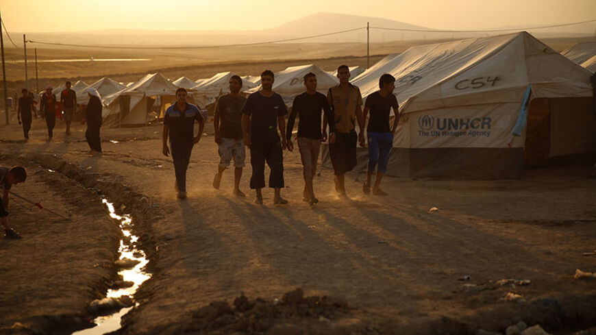 Iraqi refugees, who fled from the violence in Mosul, walk during sunset inside the Khazer refugee camp on the outskirts of Arbil, in Iraq's Kurdistan region, June 27, 2014. Grand Ayatollah Ali Sistani, the most influential Shi'ite cleric in Iraq, called on the country's leaders on Friday to choose a prime minister within the next four days, a dramatic political intervention that could hasten the end of Nuri al-Maliki's eight year rule. REUTERS/Ahmed Jadallah (IRAQ - Tags: CIVIL UNREST POLITICS SOCIETY) - RT
