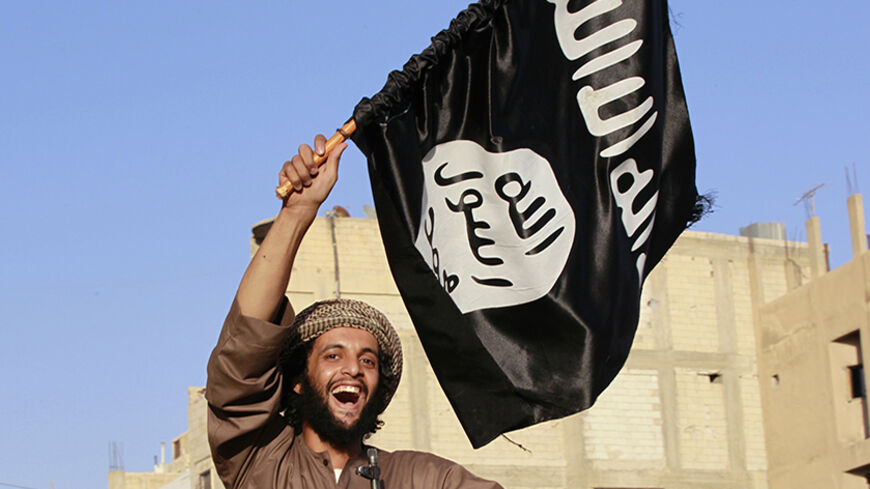 A militant Islamist fighter waving a flag, cheers as he takes part in a military parade along the streets of Syria's northern Raqqa province June 30, 2014. The fighters held the parade to celebrate their declaration of an Islamic "caliphate" after the group captured territory in neighbouring Iraq, a monitoring service said. The Islamic State, an al Qaeda offshoot previously known as Islamic State in Iraq and the Levant (ISIL), posted pictures online on Sunday of people waving black flags from cars and holdi