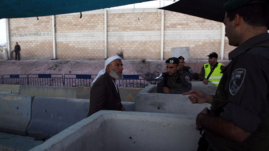 An Israeli border police officer speaks with a Palestinian man as he waits to cross into Jerusalem to attend the first Friday prayer of Ramadan in al-Aqsa mosque, at Qalandia checkpoint near the West Bank city of Ramallah July 4, 2014. REUTERS/Mohamad Torokman (WEST BANK - Tags: POLITICS RELIGION SOCIETY) - RTR3X1TV