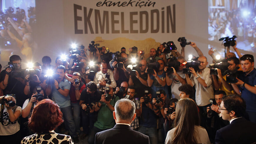Turkish main opposition presidential candidate Ekmeleddin Ihsanoglu (2nd L, back to camera) is surrounded by the media during a news conference to start his election campaign, in Istanbul, July 10, 2014. The secularist Republican People's Party (CHP) and the Nationalist Movement Party (MHP) nominated Ihsanoglu, who stepped down in December as head of the Organisation of Islamic Cooperation (OIC), as their joint candidate for the presidential race.  The first round of voting in the presidential election will