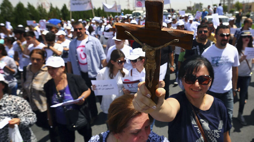 A Christian woman carries a cross during a demonstration against militants of the Islamic State, formerly known as the Islamic State in Iraq and the Levant (ISIL), in Arbil, north of Baghdad July 24, 2014. Hundreds of Iraqi Christians marched to the United Nations office in Arbil city on Thursday calling for help for families who fled in the face of threats by Islamic State militants. REUTERS/Stringer (IRAQ - Tags: CIVIL UNREST POLITICS TPX IMAGES OF THE DAY) - RTR400H7