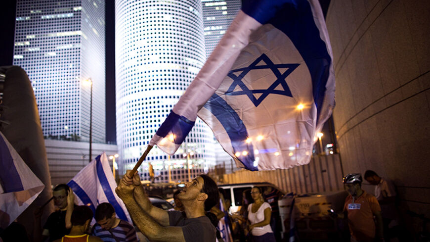 A right wing activist waves a flag during a protest in support of Israel's offensive in the Gaza Strip, in Tel Aviv July 29, 2014. An Israeli television station retracted its report on Tuesday that a ceasefire in the Gaza conflict had been agreed, saying instead there was "movement" toward a truce between Israel and the Palestinian territory's dominant Hamas Islamists being brokered by Egypt.  REUTERS/Ronen Zvulun (ISRAEL - Tags: POLITICS CIVIL UNREST) - RTR40KAT
