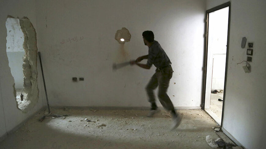 A rebel fighter knocks a hole in a wall inside a room at Karm al-Tarab frontline in Aleppo July 30, 2014. Picture taken July 30, 2014. REUTERS/Hamid Khatib   (SYRIA - Tags: POLITICS CONFLICT) - RTR40SK6