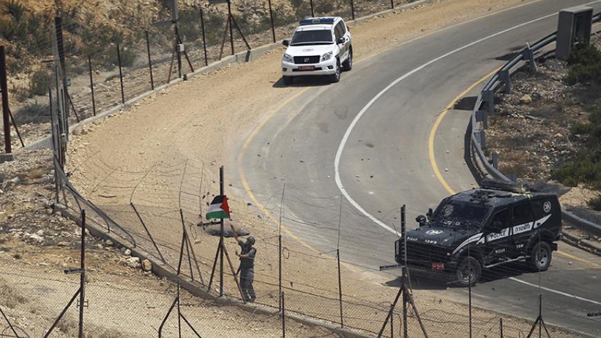 An Israeli border police removes a Palestinian flag at the Israeli barrier fence during clashes with Palestinian protesters following the funeral of Palestinian Oday Jaber, whom medics said was killed by Israeli troops during Friday clashes at a protest against the Israeli offensive in Gaza, in the West Bank village of Rafat near Ramallah August 2, 2014. Israeli forces killed two Palestinians in clashes in the occupied West Bank on Friday, Palestinian medical officials said. The violence erupted when a few 