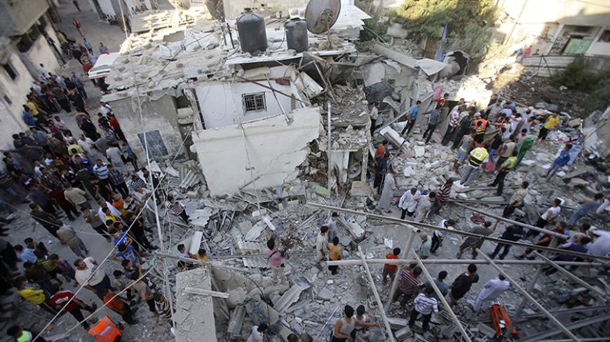 Rescue workers search for victims as Palestinians gather around the wreckage of a house, which witnesses said was destroyed in an Israeli air strike that killed at least nine members from the al-Ghol family, in Rafah in the southern Gaza Strip August 3, 2014. Renewed Israeli shelling killed at least 30 people in Gaza on Sunday after Prime Minister Benjamin Netanyahu vowed to keep up pressure on Hamas even after the army completes its core mission of destroying a tunnel network that extends into Israel. Shel