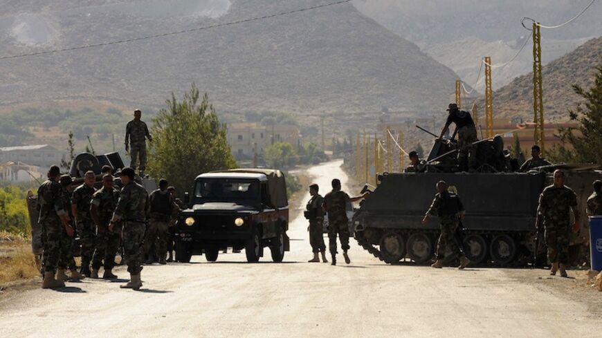 Lebanese army soldiers stand near their vehicles at the entrance leading to Arsal August 3, 2014. Following the death of eight Lebanese soldiers killed in clashes with Islamist militants in the area on Saturday, the Lebanese army deployed more troops around the town of Arsal, near the Syrian border. REUTERS/Hassan Abdallah (LEBANON - Tags: POLITICS CIVIL UNREST MILITARY) - RTR41268