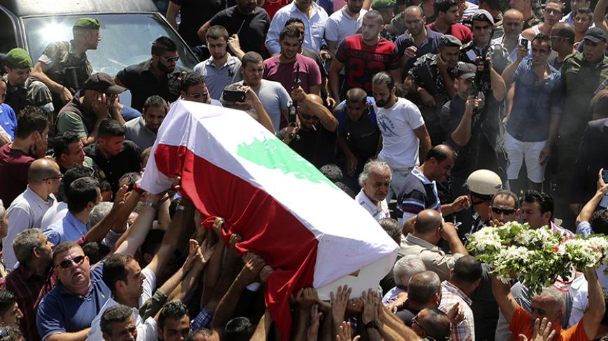 Men fire in the air as mourners carry the coffin of Lieutenant Colonel Nour Eddine al-Jamal, who was killed during Sunday's fighting between Lebanese army soldiers and Islamist militants in Arsal, during his funeral in Basta area in Beirut August 4, 2014. The Lebanese army advanced on Monday into a border town attacked by Islamists at the weekend in the most serious spillover of the three-year-old Syrian civil war into Lebanon. The military pounded areas around the town of Arsal with artillery for a third d