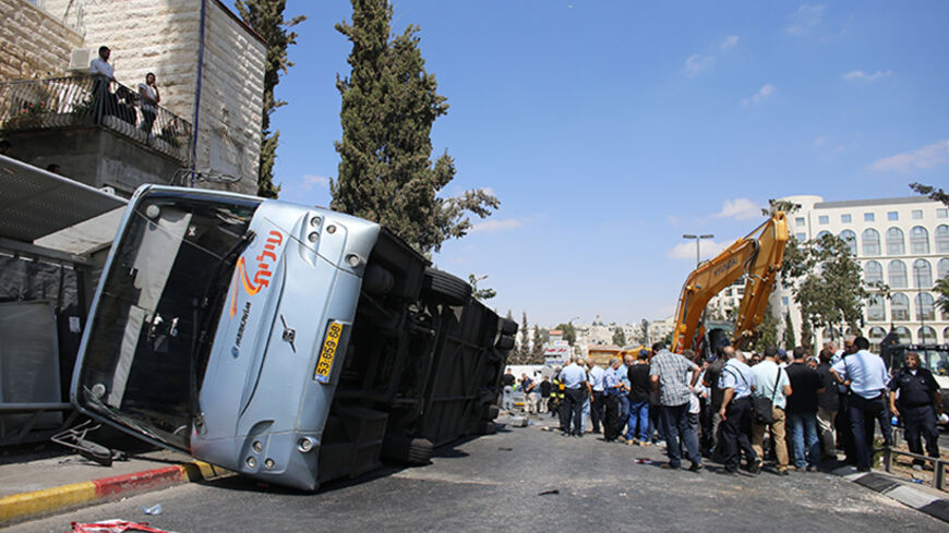 An overturned bus lies at the scene of a suspected attack in Jerusalem August 4, 2014. A construction vehicle hit and killed a pedestrian and overturned the bus on a main street in Jerusalem on Monday in what police suspect was a Palestinian attack, which ended when policemen shot dead the driver of the yellow excavator. REUTERS/Ammar Awad (JERUSALEM - Tags: POLITICS CIVIL UNREST) - RTR41625
