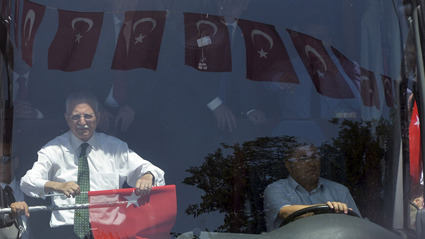 Turkey's main opposition presidential candidate Ekmeleddin Ihsanoglu (L) tours the city as part of his election campaign as Turkish flags are reflected on the window of his campaign bus in Ankara August 4, 2014. Turkey will vote for its first directly-elected president on August 10. REUTERS/Stringer (TURKEY - Tags: POLITICS ELECTIONS) - RTR416GA