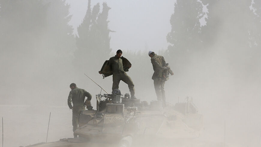 Israeli soldiers take off their jackets as they stand atop a tank after returning to Israel from Gaza August 5, 2014. Israel pulled its ground forces out of the Gaza Strip on Tuesday and started a 72-hour ceasefire with Hamas mediated by Egypt as a first step towards negotiations on a more enduring end to the month-old war. REUTERS/Baz Ratner (ISRAEL - Tags: POLITICS CONFLICT CIVIL UNREST MILITARY) - RTR41AVX