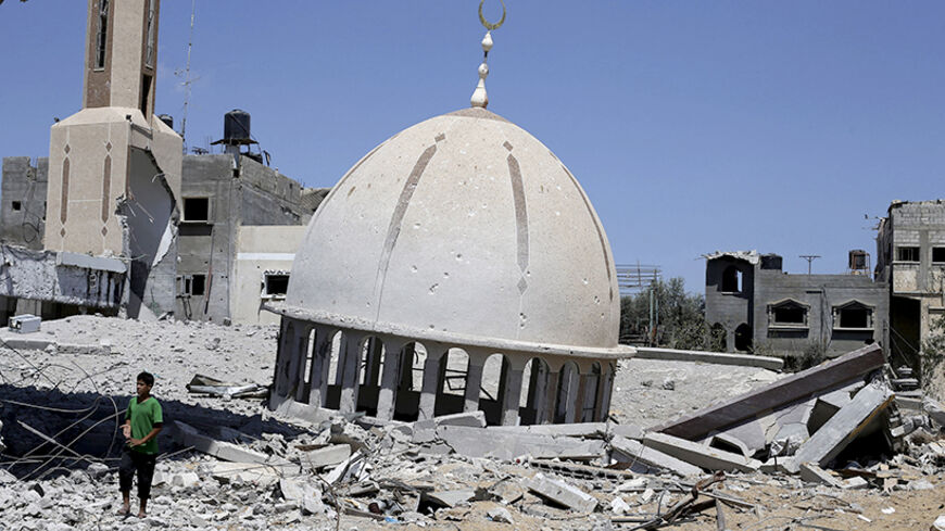 A Palestinian boy stands next to the remains of a mosque in Khuzaa town, which witnesses said was heavily hit by Israeli shelling and air strikes during Israeli offensive, in the east of Khan Younis in the southern Gaza Strip August 6, 2014. With its spacious villas and palm-lined streets, the town of Khuzaa in southern Gaza gave Palestinians a rare place to spend their free time before it was bombed and shelled to rubble last month. Largely free of the local tensions and feuds found in other neighbourhoods