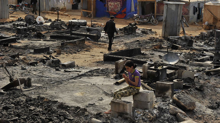 A Syrian refugee girl sits on cement blocks amid damage and burnt tents from the fighting between Lebanese army soldiers and Islamist militants in the Sunni Muslim border town of Arsal, in eastern Bekaa Valley August 7, 2014. Militant Islamists have mostly withdrawn from the Lebanese border town of Arsal, which they seized at the weekend, taking with them captive Lebanese soldiers, militant and security sources said on Thursday, as a truce to end the deadly battle appeared to hold. REUTERS/Hassan Abdallah (