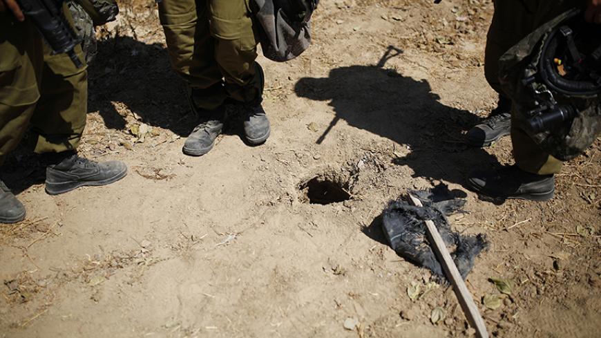 Israeli soldiers stand next to a hole in the ground they suspect is connected to a tunnel, outside the Gaza Strip August 10, 2014. Israel has accepted a new Gaza ceasefire proposed by Egyptian mediators and will send negotiators to Cairo on Monday if the truce holds, Israeli officials said. REUTERS/Amir Cohen (ISRAEL - Tags: POLITICS CIVIL UNREST CONFLICT MILITARY TPX IMAGES OF THE DAY) - RTR41VLW