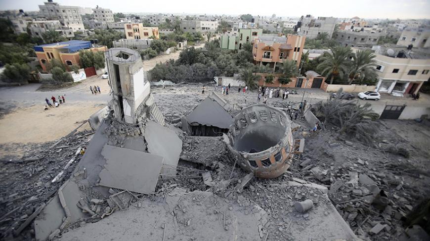 Palestinians gather around the remains of a mosque, which witnesses said was destroyed in an Israeli air strike before a 72-hour truce, in Khan Younis in the southern Gaza Strip August 11, 2014. Israeli negotiators were due in Cairo on Monday for talks on ending a month-old Gaza war with Palestinian militants, an Israeli government official said, after a new 72-hour truce brokered by Egypt appeared to be holding.  REUTERS/Ibraheem Abu Mustafa (GAZA - Tags: POLITICS CIVIL UNREST RELIGION TPX IMAGES OF THE DA