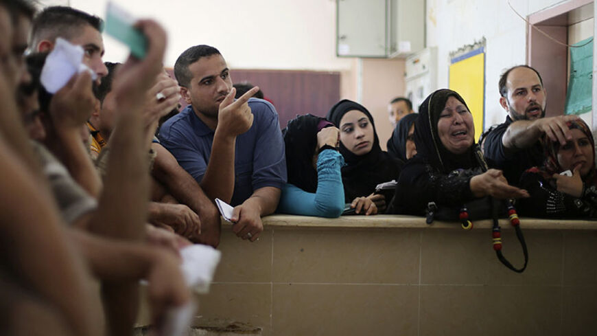 A Palestinian woman, hoping to cross into Egypt, cries as she waits with others at the Rafah crossing between Egypt and the southern Gaza Strip August 12, 2014. Under Egyptian President Abdel Fattah al-Sisi, Cairo has secured closures on the Gaza border, increasing economic pressure on Hamas from a long-running Israeli blockade. Talks to end a month-long war between Israel and Islamist militants in Gaza have made no progress so far, an Israeli official said on Tuesday, as a 72-hour ceasefire in the shattere