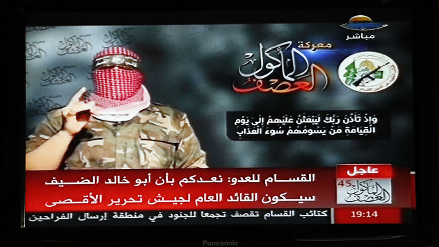 Abu Ubaida, the spokesman of the Izz el-Deen al-Qassam Brigade, the armed wing of the Hamas movement, is pictured on a television screen as he delivers a televised statement on Hamas TV, in Gaza August 20, 2014. Hamas's military wing said on Wednesday an Israeli air strike in Gaza had failed to kill its military commander, Mohammed Deif. In a televised statement, Ubaida said Israel had missed its target. Deif's wife and seven-month-old son were killed in the attack. REUTERS/Suhaib Salem (GAZA - Tags: POLITI