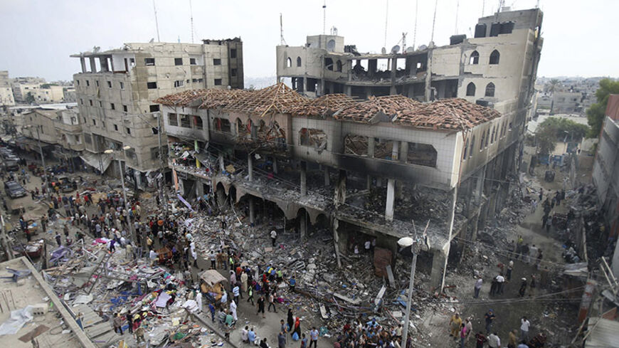Palestinians gather around the remains of a commercial center, which witnesses said was hit by an Israeli air strike on Saturday, in Rafah in the southern Gaza Strip August 24, 2014. Egypt called on Israel and the Palestinians on Saturday to halt hostilities and resume peace talks, but both sides kept up attacks, including an Israeli air strike which destroyed a residential tower block in the centre of Gaza City. Hamas militants also fired rockets at Israel, hitting the southern city of Beersheba, where two