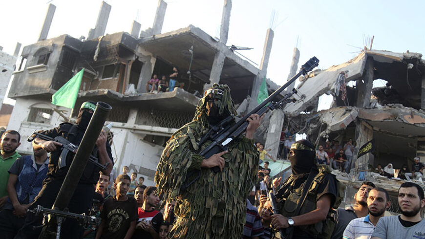 Hamas militants display weapons as they celebrate what they say was a victory over Israel, in front of a destroyed house in the Shejaia neighborhood east of Gaza City August 27, 2014. An open-ended ceasefire in the Gaza war held on Wednesday as Prime Minister Benjamin Netanyahu faced strong criticism in Israel over a costly conflict with Palestinian militants in which no clear victor emerged. REUTERS/Majdi Fathi (GAZA - Tags: POLITICS CONFLICT TPX IMAGES OF THE DAY) - RTR440CH
