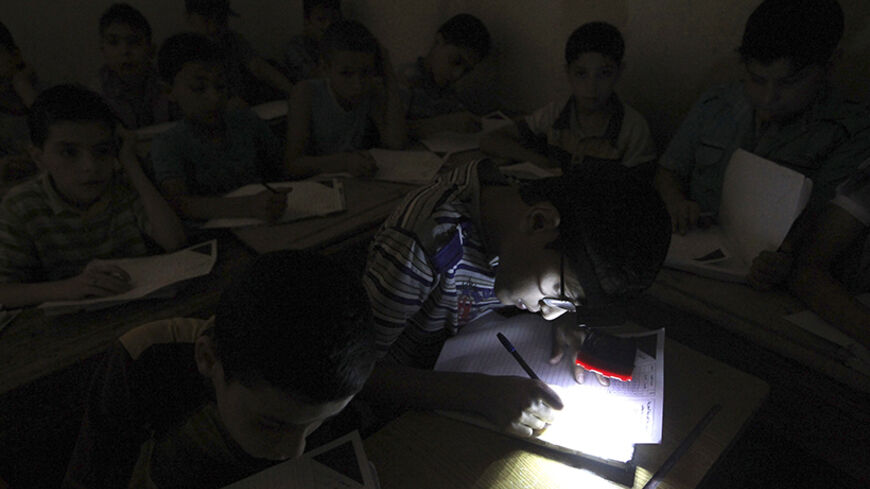 A student wears a headlight, due to electricity shortage, as he takes his year-end examinations at a school in Aleppo's al-Sha'ar district June 5, 2013. REUTERS/Muzaffar Salman (SYRIA - Tags: CONFLICT EDUCATION SOCIETY) - RTX10CK8