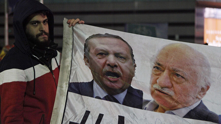 A demonstrator hold pictures of Turkey's Prime Minister Tayyip Erdogan and Turkish cleric Fethullah Gulen (R), during a protest against Turkey's ruling AK Party (AKP), demanding the resignation of Erdogan, in Istanbul December 30, 2013. Erdogan swore on Sunday he would survive a corruption crisis circling his cabinet, saying those seeking his overthrow would fail just like mass anti-government protests last summer. Gulen denies involvement in stirring up the graft case, but he regularly censures Erdogan, a 