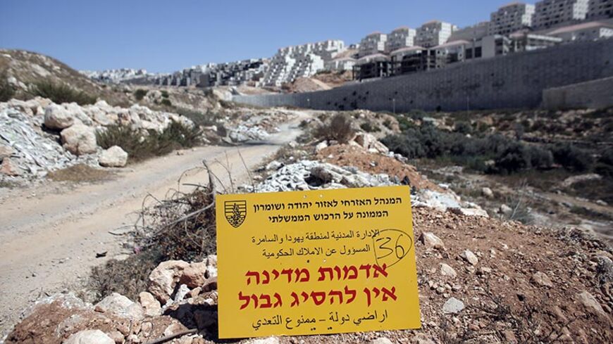 An official Israeli sign from the Civil Administration in Charge of the Government Property, placed in the West Bank near the Israeli Beitar Illit (R) settlement, states that the area is state land and trespassing is not allowed, near the Palestinian village of Wadi Fukin, on September 4, 2014. Israel over the weekend said it would expropriate 400 hectares (988 acres) of Palestinian land around Bethlehem, and allowed 45 days for any appeal. AFP PHOTO / AHMAD GHARABLI        (Photo credit should read AHMAD G