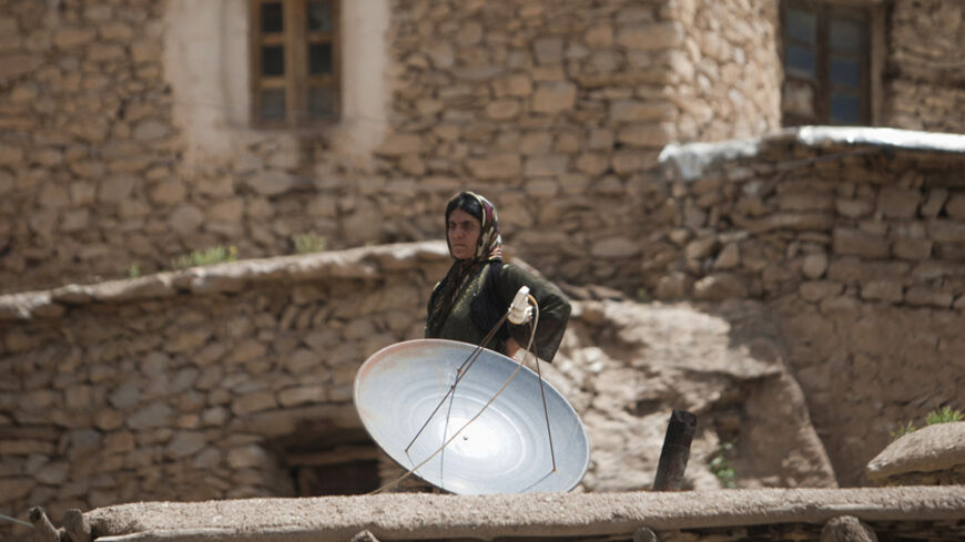An Iranian Sunni Kurd woman stands behind a satellite dish on her home's rooftop at Palangan village in Kurdistan province, about 660 km (412 miles) southwest of Tehran May 11, 2011. Iranian Shi'ite and Sunni Kurds live in harmony with each other in Palangan, although Sunni is the religion of the majority of the people. REUTERS/Morteza Nikoubazl (IRAN - Tags: SOCIETY RELIGION BUSINESS) - RTR2MADK