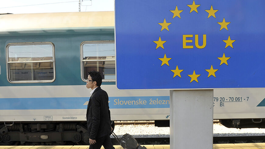 A passenger walks past a European Union sign at the border cross with Croatia in Dobova June 15, 2011. In December 2007, the European Union lifted land and sea border checks with Slovenia. Airport checks were also abolished in December 2008 following the signing of the Schengen Agreement. REUTERS/Srdjan Zivulovic (SLOVENIA - Tags: TRANSPORT POLITICS) - RTR2NPCI