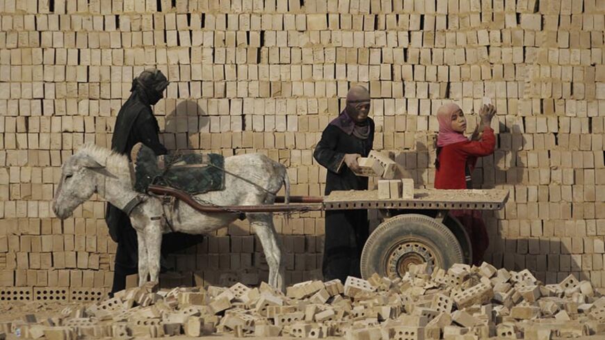 Female workers load bricks on a donkey driven cart in a brick factory in the town of Nahrawan east of Baghdad, March 8, 2012. REUTERS/Thaier al-Sudani     (IRAQ - Tags: SOCIETY BUSINESS EMPLOYMENT ANIMALS) - RTR2Z1E9