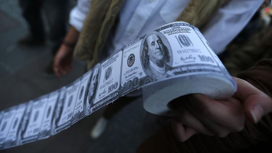 A demonstrator holds toilet paper made from fake U.S. dollars during a protest against Turkey's Prime Minister Tayyip Erdogan and his ruling Ak Party (AKP) government in Ankara February 27, 2014. An audio recording purporting to be of Erdogan giving his son business advice has been published on YouTube, following one earlier in the week that fuelled a corruption scandal and unnerved markets. Erdogan said a similar post on the video-sharing site YouTube on Monday, allegedly of him telling his son Bilal to di
