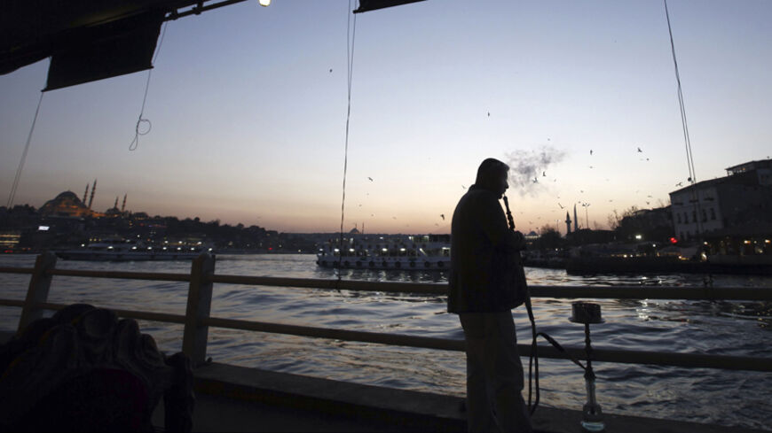 A man smokes his waterpipe at the Galata bridge in Istanbul, April 8, 2014. REUTERS/Osman Orsal (TURKEY - Tags: SOCIETY) - RTR3KG89