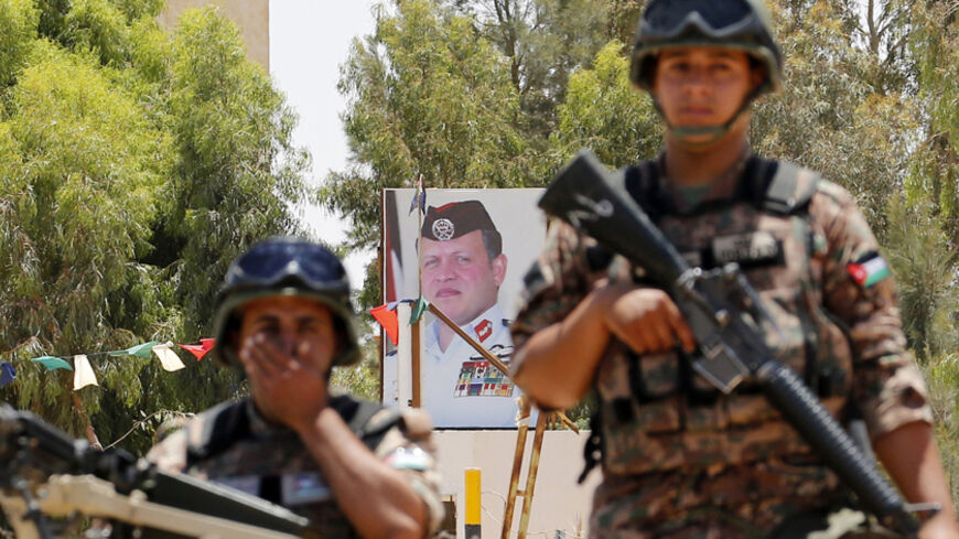 Jordanian soldiers stand guard in front of a poster for Jordan's King Abdullah near the Jordanian Karameh border crossing on the Jordanian-Iraqi border, near Ruweished city June 25, 2014. REUTERS/Muhammad Hamed (JORDAN - Tags: POLITICS CIVIL UNREST MILITARY ROYALS) - RTR3VOW9
