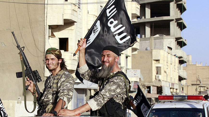Militant Islamist fighters wave flags as they take part in a military parade along the streets of Syria's northern Raqqa province June 30, 2014. The fighters held the parade to celebrate their declaration of an Islamic "caliphate" after the group captured territory in neighbouring Iraq, a monitoring service said. The Islamic State, an al Qaeda offshoot previously known as Islamic State in Iraq and the Levant (ISIL), posted pictures online on Sunday of people waving black flags from cars and holding guns in 