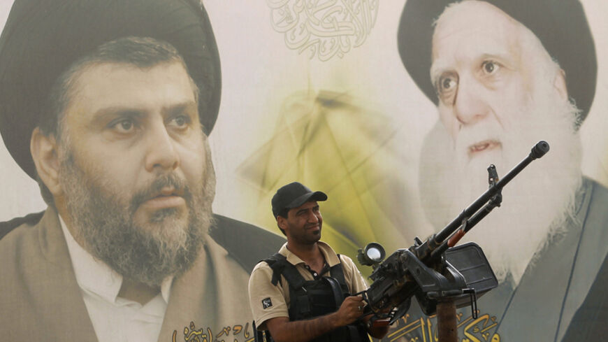 A Shi'ite volunteer from brigades loyal to radical cleric Muqtada al-Sadr, keeps guard as he mans a machine gun in front of a picture of Iraqi Shi'ite radical leader Muqtada al-Sadr (L) and the Grand Ayatollah Mohammed Sadiq al-Sadr, in Samarra, July 13, 2014.  Followers of radical cleric Muqtada al-Sadr, who fought U.S. troops under the banner of the Mehdi Army during the 2003-2011 occupation, have returned as Sadr's new "Peace Brigades." The black-turbaned cleric was shown on television this week surround