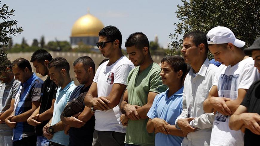 The Dome of the Rock is seen in the background as Palestinians pray on the third Friday of the holy month of Ramadan in the Arab east Jerusalem neighbourhood of Ras al-Amud July 18, 2014. An Israeli police spokesman said on Friday that police allowed only Palestinian men over the age of 50 to enter a compound which houses Al-Aqsa mosque and is known to Muslims as Noble Sanctuary and to Jews as Temple Mount in Jerusalem's Old City. He added that seven people were detained on suspicion of throwing stones at p