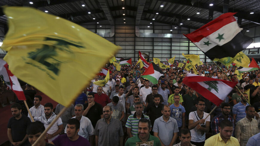 Hezbollah supporters wave Lebanese, Syrian, Palestinian and Hezbollah flags as they listen to their leader Sayyed Hassan Nasrallah addressing his supporters during a rally to mark "Quds (Jerusalem) Day" in Beirut's southern suburbs July 25, 2014. REUTERS/Sharif Karim    (LEBANON - Tags: POLITICS CIVIL UNREST RELIGION) - RTR4056R