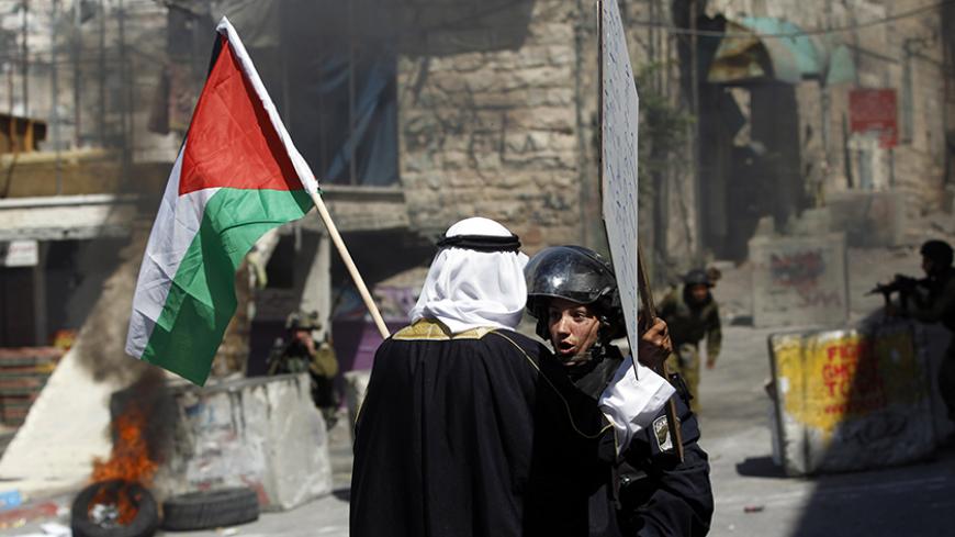 A Palestinian man holding a Palestinian national flag argues with an Israeli policewoman, during a protest against the Israeli offensive in Gaza, in the West Bank city of Hebron August 22, 2014. REUTERS/Mohamad Torokman (WEST BANK - Tags: POLITICS CIVIL UNREST CONFLICT TPX IMAGES OF THE DAY) - RTR43D91