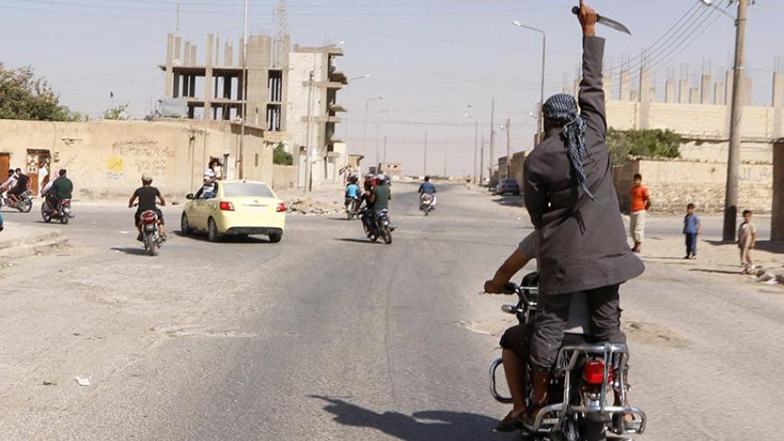 A man holds up a knife as he rides on the back of a motorcycle touring the streets of Tabqa city with others in celebration after Islamic State militants took over Tabqa air base, in nearby Raqqa city August 24, 2014. Islamic State militants stormed the air base in northeast Syria on Sunday, capturing most of it from government forces after days of fighting over the strategic location, a witness and a monitoring group said. Fighting raged inside the walls of the Tabqa air base, the Syrian army's last footho