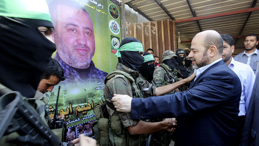 Hamas political leader Moussa Abu Marzouk (R) shakes hands with a Hamas militant as he visits the mourning tent of senior Hamas commander Mohammed Abu Shammala (seen in posters), who was killed by an Israeli air strike during the seven-week Israeli offensive, in Rafah in the southern Gaza Strip August 28, 2014. Abu Marzouk, who is currently based in Egypt, arrived in Gaza on Thursday. An open-ended ceasefire in the Gaza war held on Wednesday as Israeli Prime Minister Benjamin Netanyahu faced strong criticis