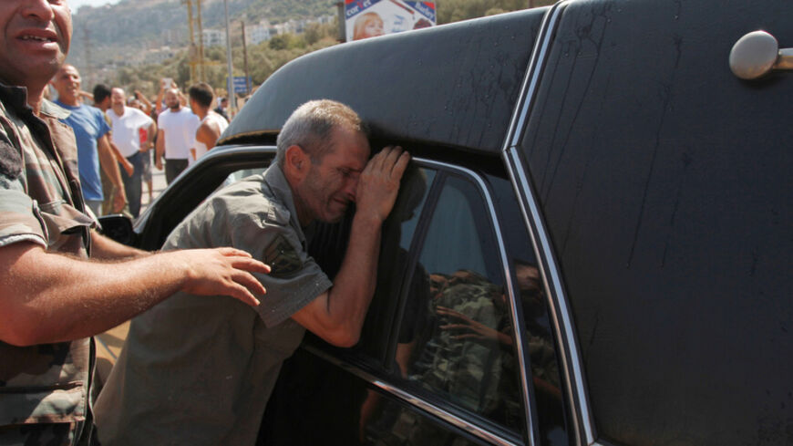 A father of a Lebanese soldier captured by hardline Syrian Islamists, reacts next to a hearse carrying the coffin of another soldier Ali al-Sayyed, who was beheaded by Islamic State militants in Arsal, during his funeral in Qalamoun, in Akkar September 3, 2014. Islamic State militants beheaded al-Sayyed, one of 19 Lebanese soldiers captured by hardline Syrian Islamists when they seized the Lebanese border town for a few days last month, a video posted on social media showed on Saturday.   REUTERS/Omar Ibrah