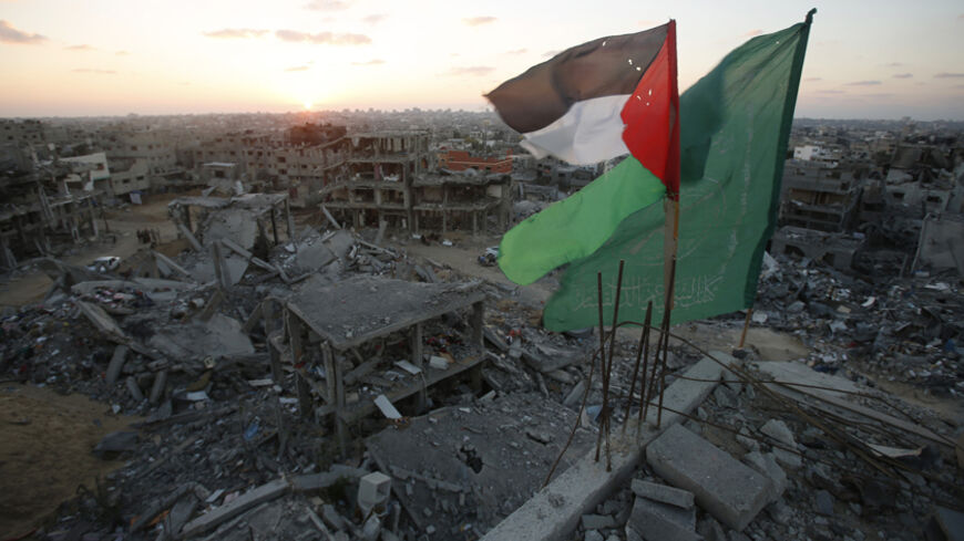 A Palestinian flag and a Hamas flag (R) flutter atop the wreckage of a house, which witnesses said was destroyed during the seven-week Israeli offensive, in the east of Gaza City September 3, 2014. Fifty days of war in one of the most densely populated parts of the world have left swathes of Gaza in ruins. With the economy reeling under an Israeli-Egyptian blockade, the enclave now faces an almost impossible task of rebuilding. Picture taken September 3, 2014.  REUTERS/Suhaib Salem (GAZA - Tags: CIVIL UNRES