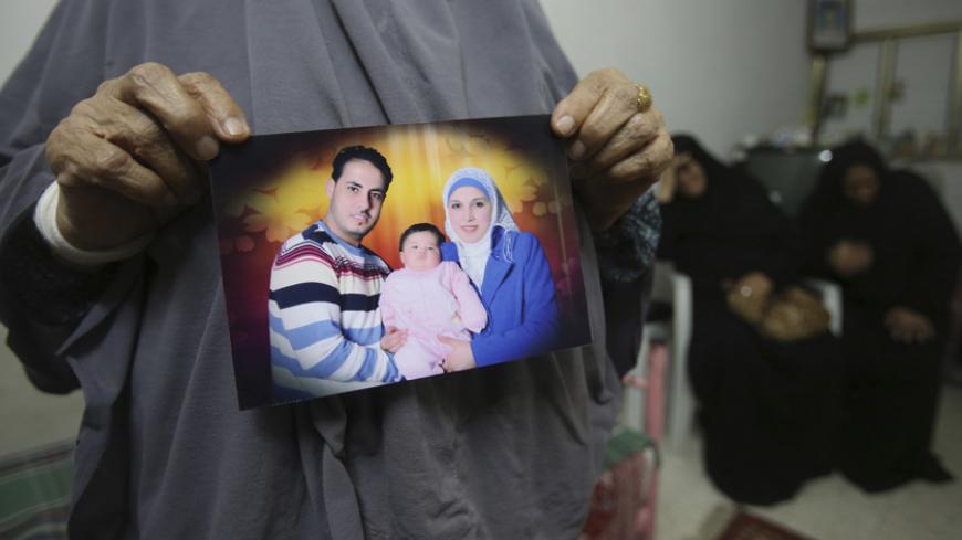 The mother of Palestinian Shukri al-Assouli holds a picture of him with his wife and daughter at her house in Khan Younis in the southern Gaza Strip September 18, 2014. Assouli, 33, set off from Alexandria on September 6 with his wife and two children on a ship with 400 migrants on board that was destined for Italy, but the vessel sank and he was rescued by a Japanese commercial ship and taken to Greece. His family is missing.  A devastating war with Israel has swollen the number of Palestinians in the Gaza