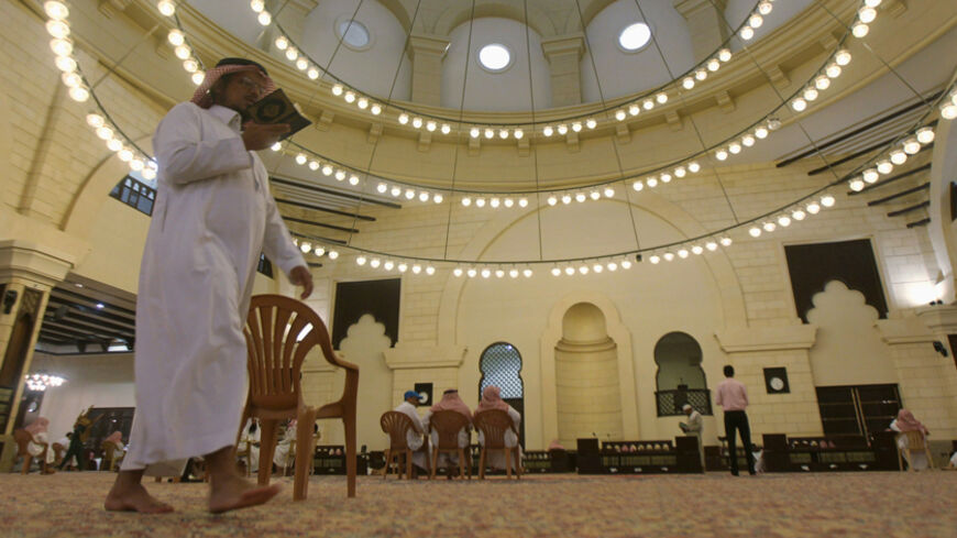 A Muslim man walks past as he reads the Koran at the Al-Rajhi mosque east of Riyadh, during the holy month of Ramadan July 24, 2013. REUTERS/Faisal Al Nasser (SAUDI ARABIA - Tags: RELIGION) - RTX11XN6