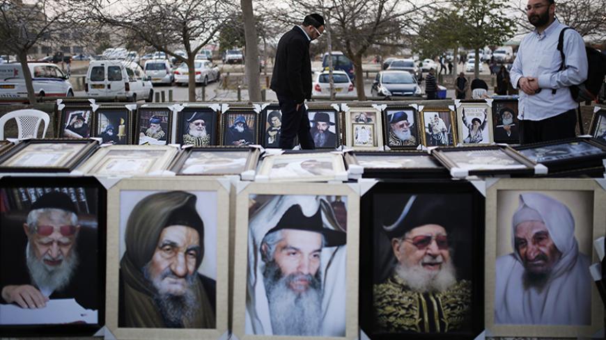 Jewish worshippers walk between images of rabbis offered for sale during an annual pilgrimage to the gravesite of Rabbi Yisrael Abuhatzeira, a Moroccan-born sage and kabbalist also known as the Baba Sali, on the anniversary of his death in the southern town of Netivot, January 5, 2014. REUTERS/Amir Cohen (ISRAEL - Tags: ANNIVERSARY RELIGION TPX IMAGES OF THE DAY) - RTX1735D