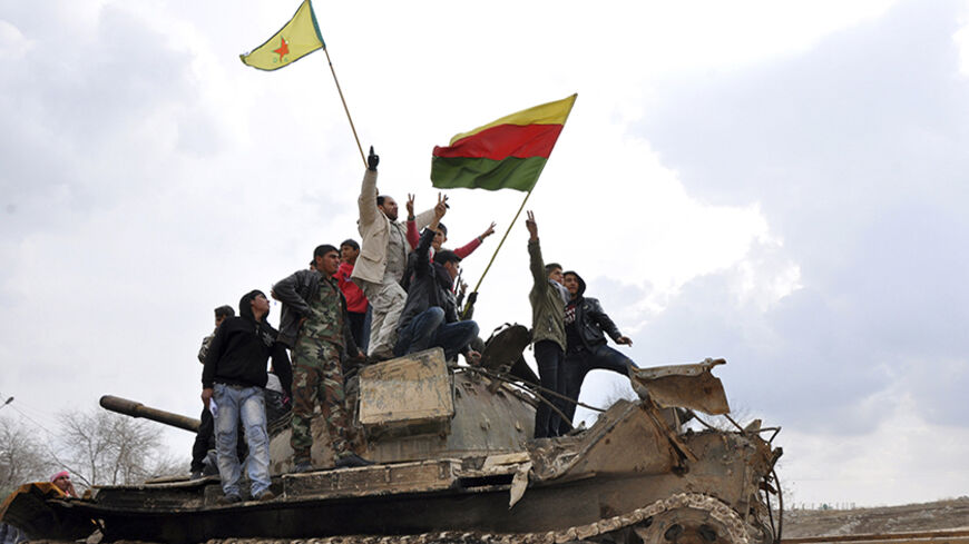 Civilians and members of the Kurdish People's Protection Units (YPG) gesture and raise flags atop a tank that belonged to fighters from the al Qaeda-affiliated Islamic State of Iraq and the Levant (ISIL), in al-Manajeer village of Ras al-Ain countryside January 28, 2014. REUTERS/Rodi Said (SYRIA - Tags: POLITICS CIVIL UNREST CONFLICT) - RTX17YNR