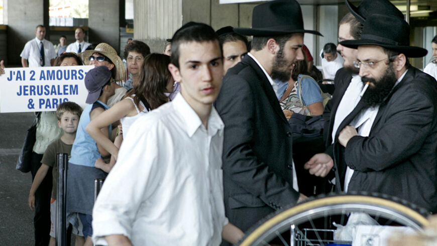 Some of 200 French Jews queue at Paris' Charles de Gaulle airport before emigrating to Israel July 28, 2004. Some 2,500 Jews leave France for Israel each year but Wednesday's departure comes less than two weeks after [Israeli Prime Minister Ariel Sharon] sparked a controversial call on French Jews to emigrate to Israel to escape what he called the 'wildest anti-Semitism'.  Sign at rear reads: "I have two loves:  Jerusalem and Paris".  ??? NOTE: Some of the people in background may have been accompanying rel