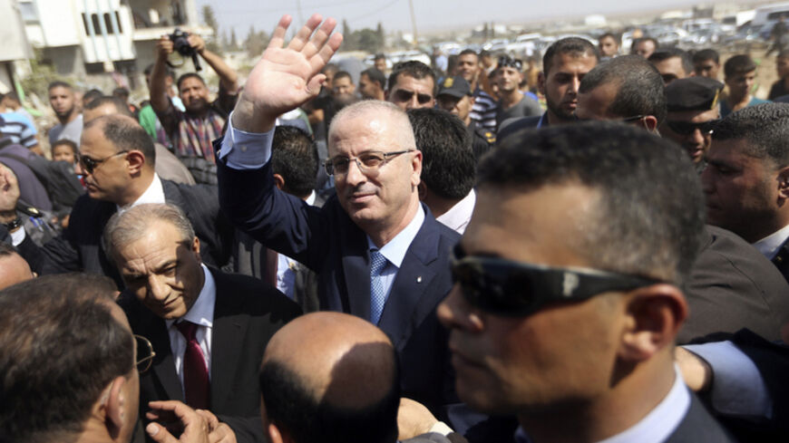 Palestinian Prime Minister Rami Hamdallah (C) waves as he visits houses that witnesses said were destroyed during the recent seven-week Israeli offensive, in the Shejaia neighbourhood, east of Gaza City October 9, 2014. Technocrat Hamdallah arrived in the Hamas-dominated Gaza Strip on Thursday to convene the first meeting of a unity government there since a brief civil war in 2007 between Hamas and forces loyal to the Fatah party. REUTERS/Ibraheem Abu Mustafa (GAZA - Tags: POLITICS CIVIL UNREST TPX IMAGES O