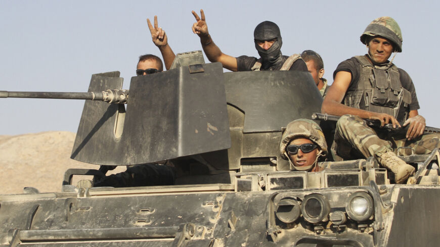 Lebanese army soldiers gesture while riding on an armoured vehicle as they exit the Sunni Muslim border town of Arsal, in eastern Bekaa Valley August 28, 2014. Gunmen killed at least one Lebanese soldier on Thursday when they attacked an army post at the border with Syria on Thursday near a town seized by Islamist insurgents earlier this month, a security source said. Three soldiers were wounded in the clash in the mountainous border zone just outside the town of Arsal, which was held for five days by milit